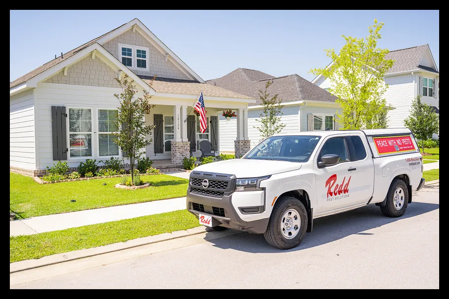 a redd pest truck in front of a house