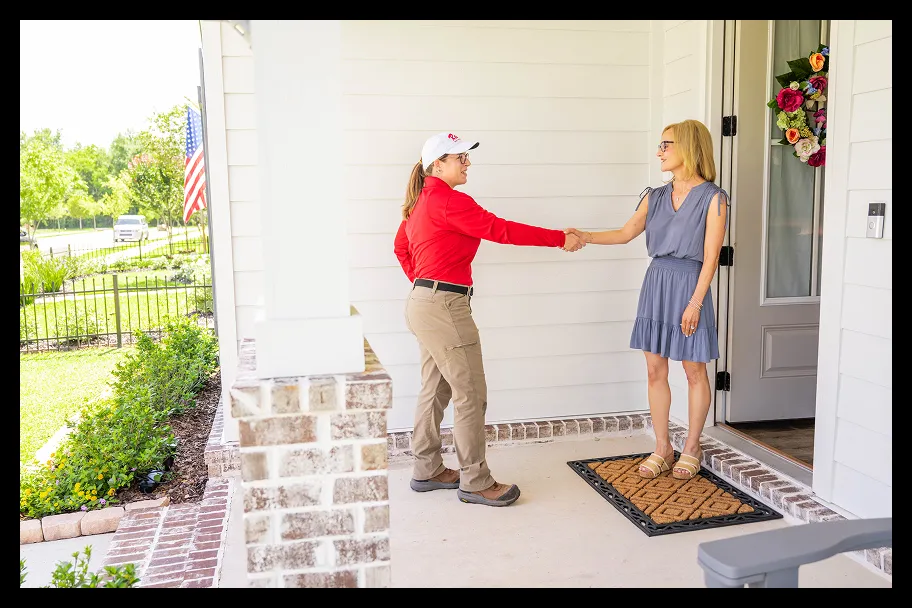an employee in front of a house shaking hands with a woman